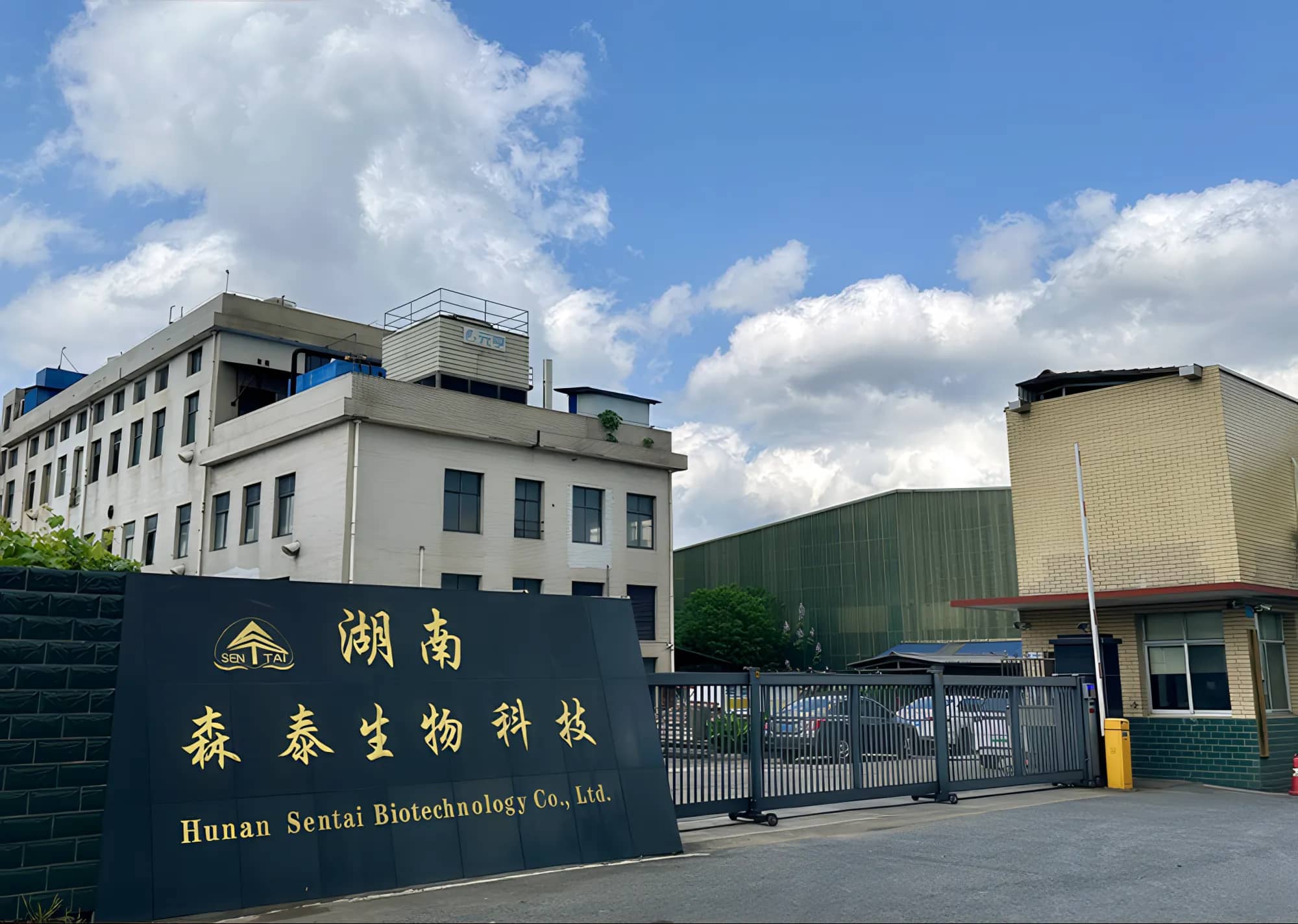 Hunan Sentai Biotechnology main gate with the company name sign, office building and plant buildings under a blue sky